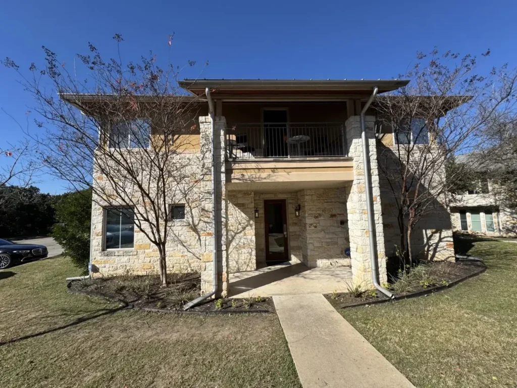 The exterior of the Austin DBT Associates office, a two-story stone building with a clear walkway to the entrance.