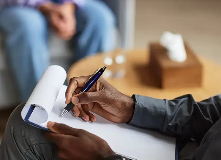 A therapist takes notes on a clipboard during an EMDR session, demonstrating the active and structured process of therapy and client support.