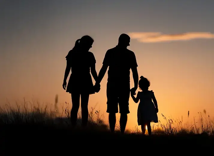Silhouette of a family (mother, father, and young child) holding hands, representing family support for child DBT.
