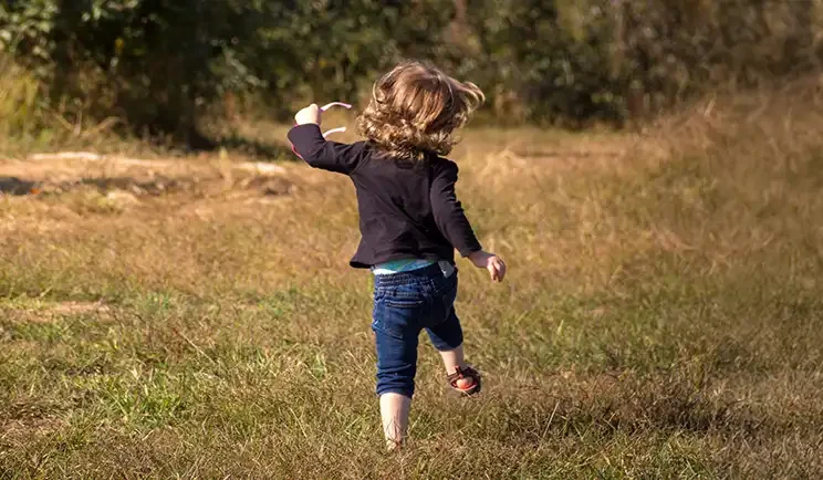 A young child running freely in a field, symbolizing active engagement and emotional growth after getting child DBT.