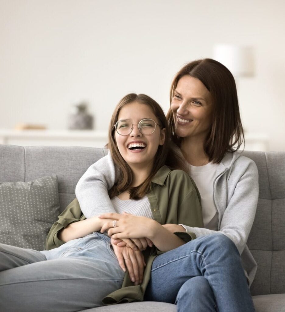 Happy mother with her teenage daughter enjoying one another's company on the couch after successful DBT Skills for Teens