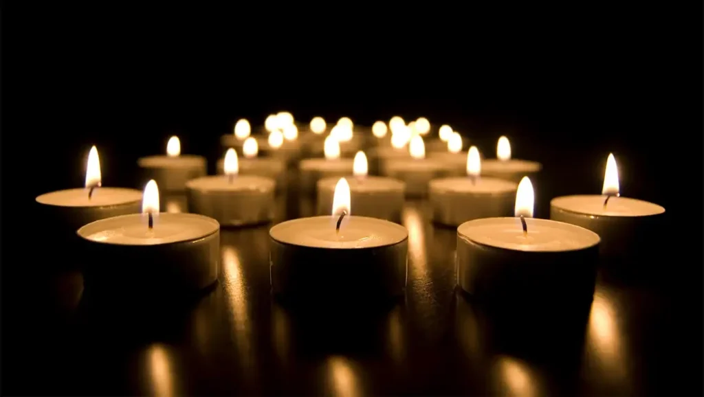 Group of lit tea light candles glowing in the dark, often used to symbolize mindfulness, hope, or meditation.