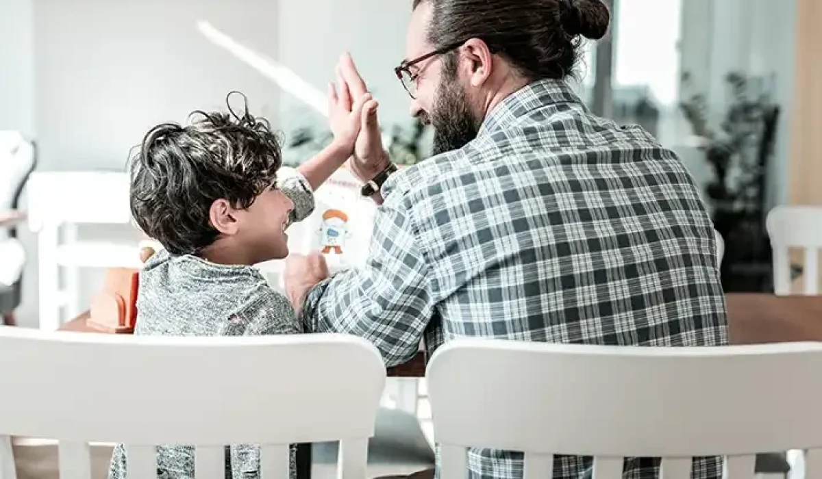 Father and son high-fiving, demonstrating improved understanding and connection after completing child DBT therapy.